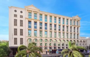 Elegant mid-rise commercial building with arched windows and a classic architectural design, surrounded by palm trees.
