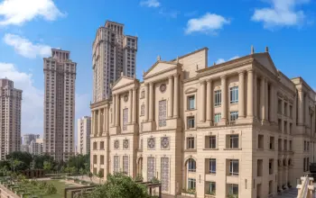 Grand neoclassical-style building with intricate detailing, surrounded by modern high-rises and greenery