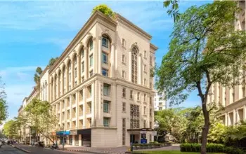 Elegant mid-rise office building with classic architectural design, surrounded by greenery.