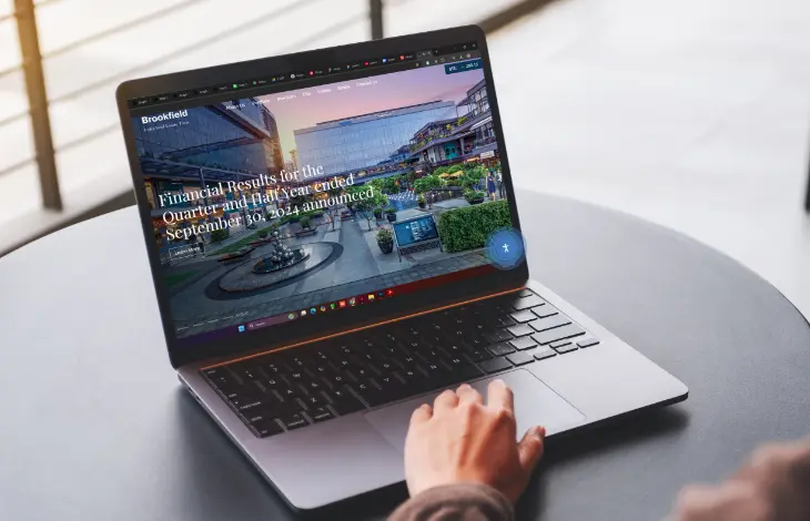 A person using a laptop to browse the Brookfield website displaying financial results for the quarter and half-year ended September 30, 2024
