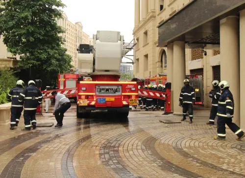 Firefighters responding to an emergency, with fire trucks and equipment deployed in front of a building.