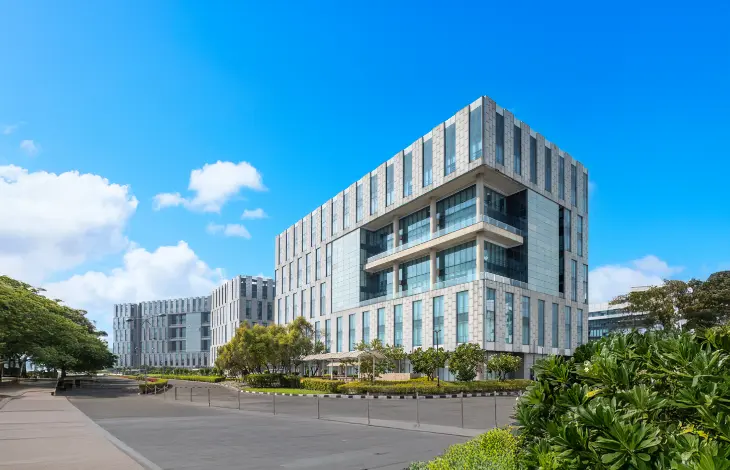 Modern office buildings at Candor TechSpace, Newtown, Kolkata, featuring contemporary architecture and green landscaping under a bright blue sky.