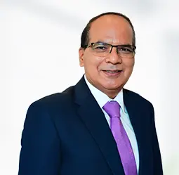 Baljit Singh, Executive Vice President - Operations, is seen smiling in a formal business suit with a purple tie, representing professionalism and leadership in a corporate environment.