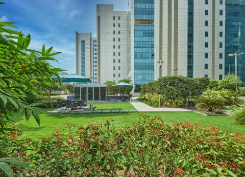 A green garden with plants and shaded seating areas, offering a peaceful outdoor space