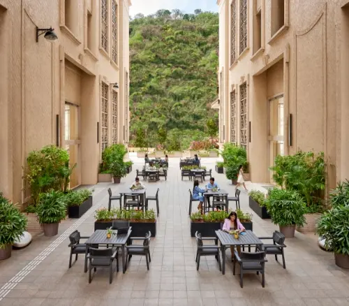 Outdoor seating area at Kensington, Downtown Powai, Mumbai, surrounded by greenery and elegant architecture.