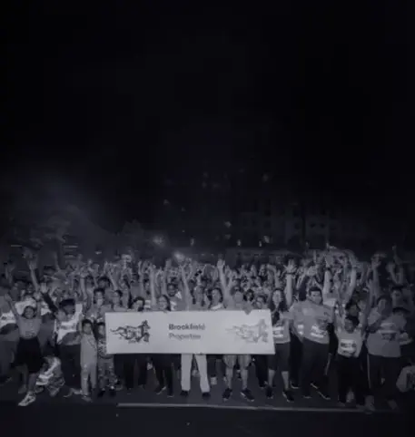 A large group of people holding a banner with the text 'Brookfield Properties' while celebrating at a night event