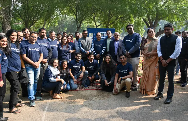 A group of Brookfield Properties employees posing together for a photo at an outdoor event, with some people in formal attire and others in matching company T-shirts