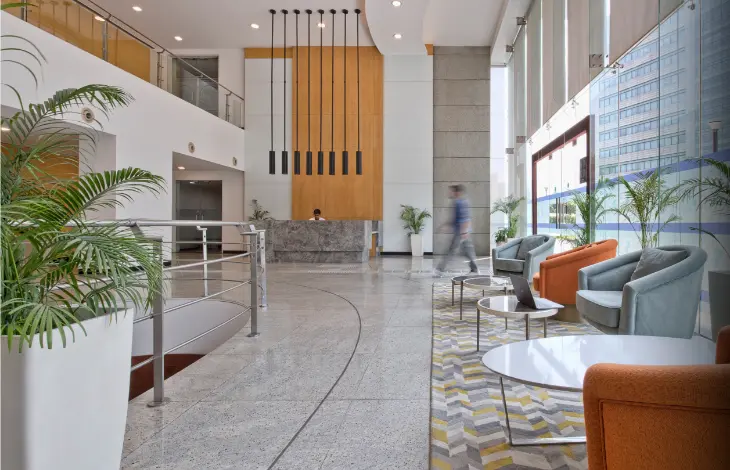 The modern lobby of Candor TechSpace, Sector 21, Gurugram, with comfortable seating, a reception desk, and large windows.