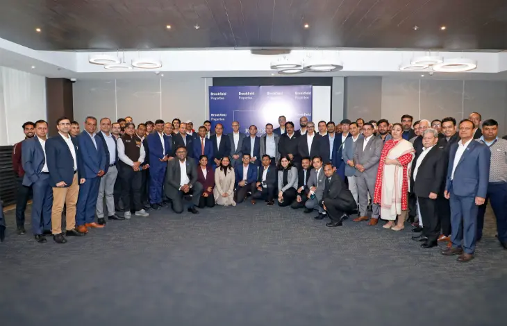 A group photo of the Brookfield Properties team at a corporate event, with individuals in business suits and formal attire posing together.