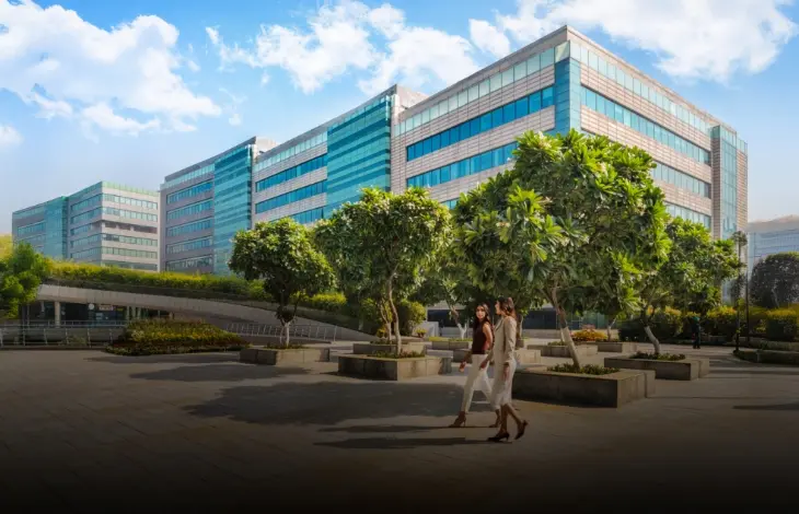Candor TechSpace, Sector 21, Gurugram, featuring modern glass office buildings and a landscaped outdoor area with trees and walkways.