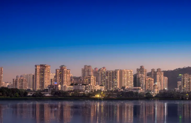 The skyline of Downtown Powai, Mumbai, with high-rise buildings reflected in the water during twilight.