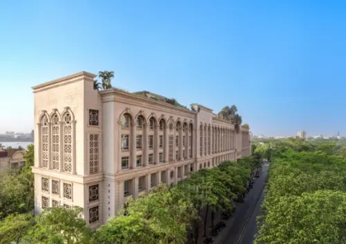 A beautiful view of the Delphi building in Downtown Powai, Mumbai, showcasing its architectural elegance with intricate details and a lush green tree-lined street in the foreground.